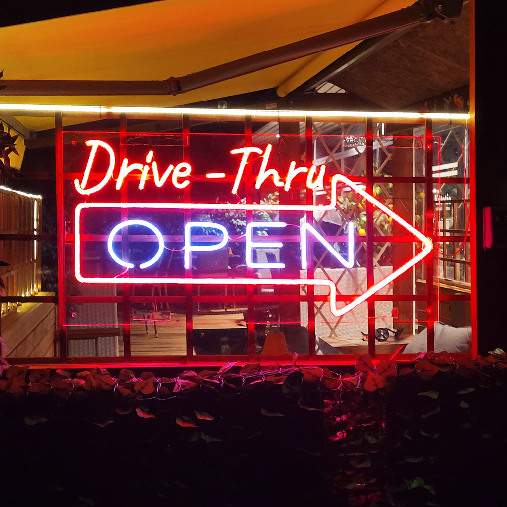 "Drive Thru Open Neonkyltti" loistaa kirkkaasti ja kutsuu asiakkaat nauttimaan ajopalvelun mukavuudesta.