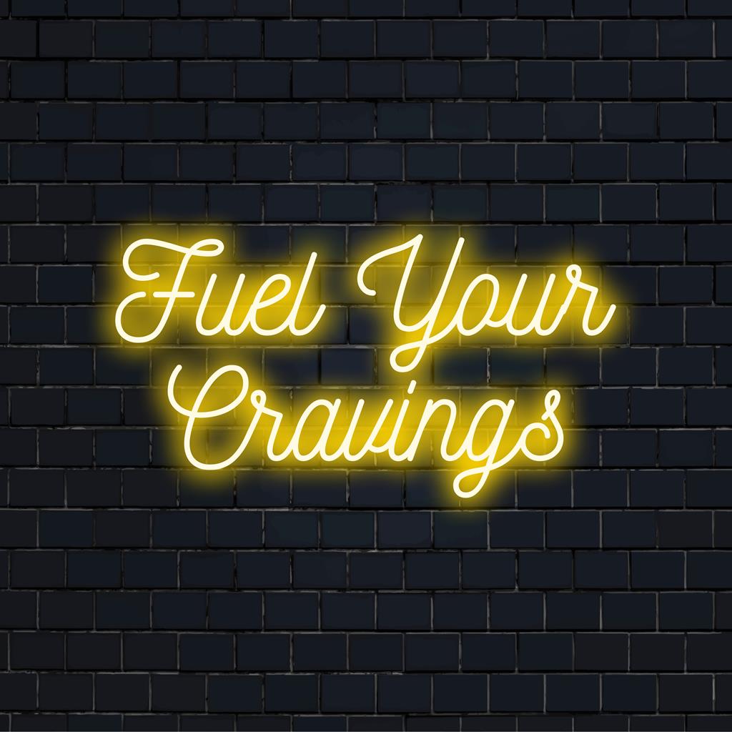 Mukautettu LED-neonkyltti ilmauksella Fuel Your Cravings, jossa on moderni typografinen muotoilu ja kirkkaat neonvärit.