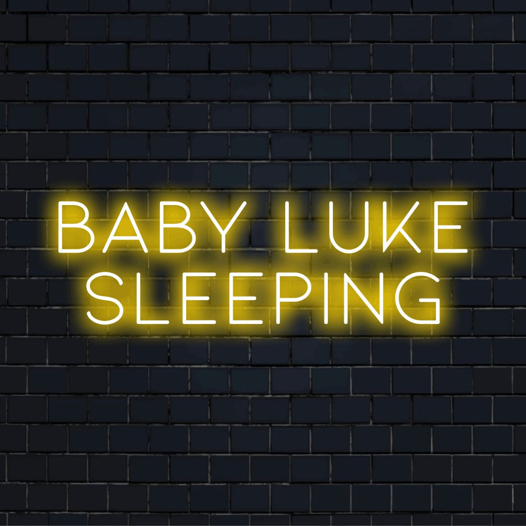 Baby Luke Sleeping Personalized Neon Light with bright neon lettering on dark brick wall