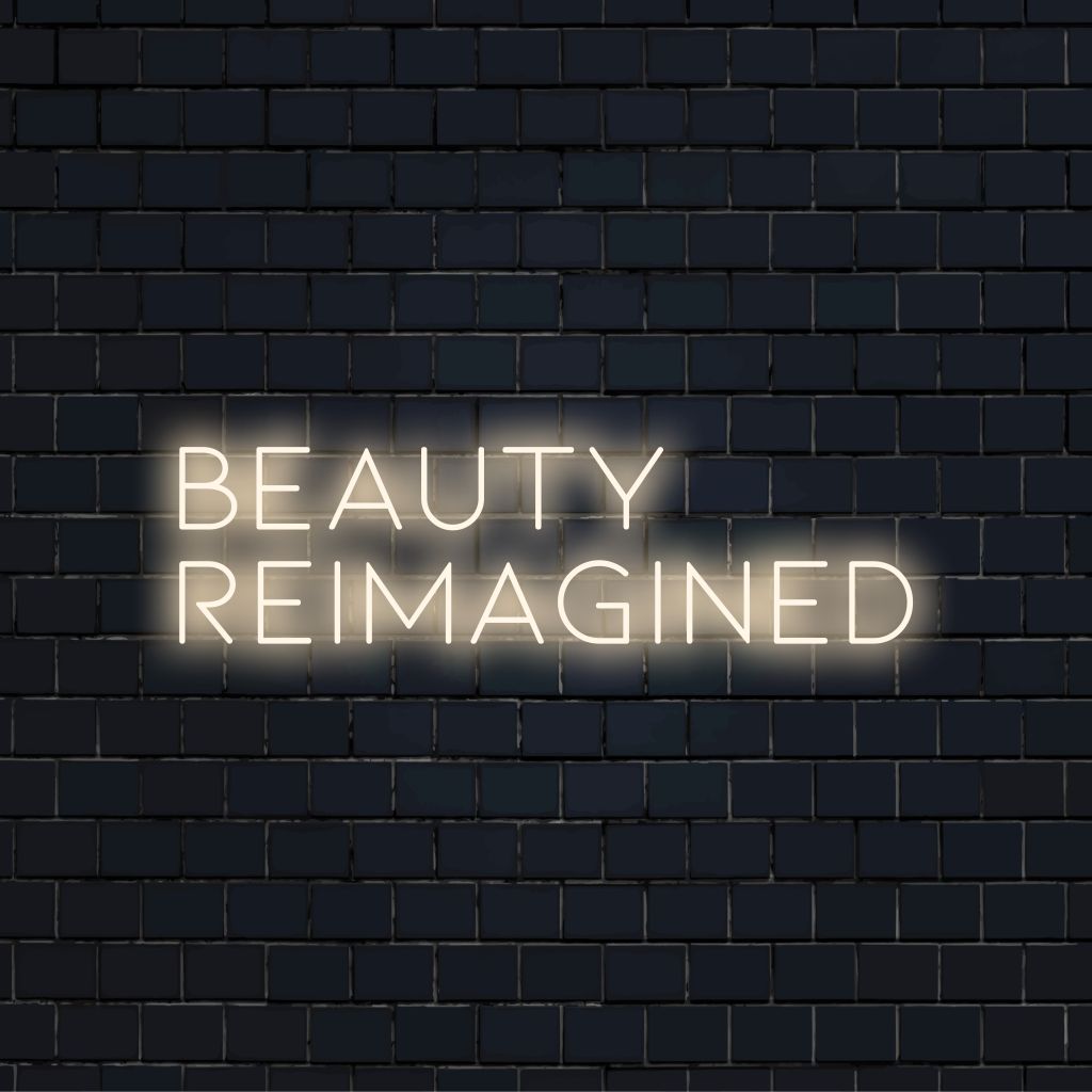 Beauty Reimagined Neon Light with bright neon lettering against black brick wall