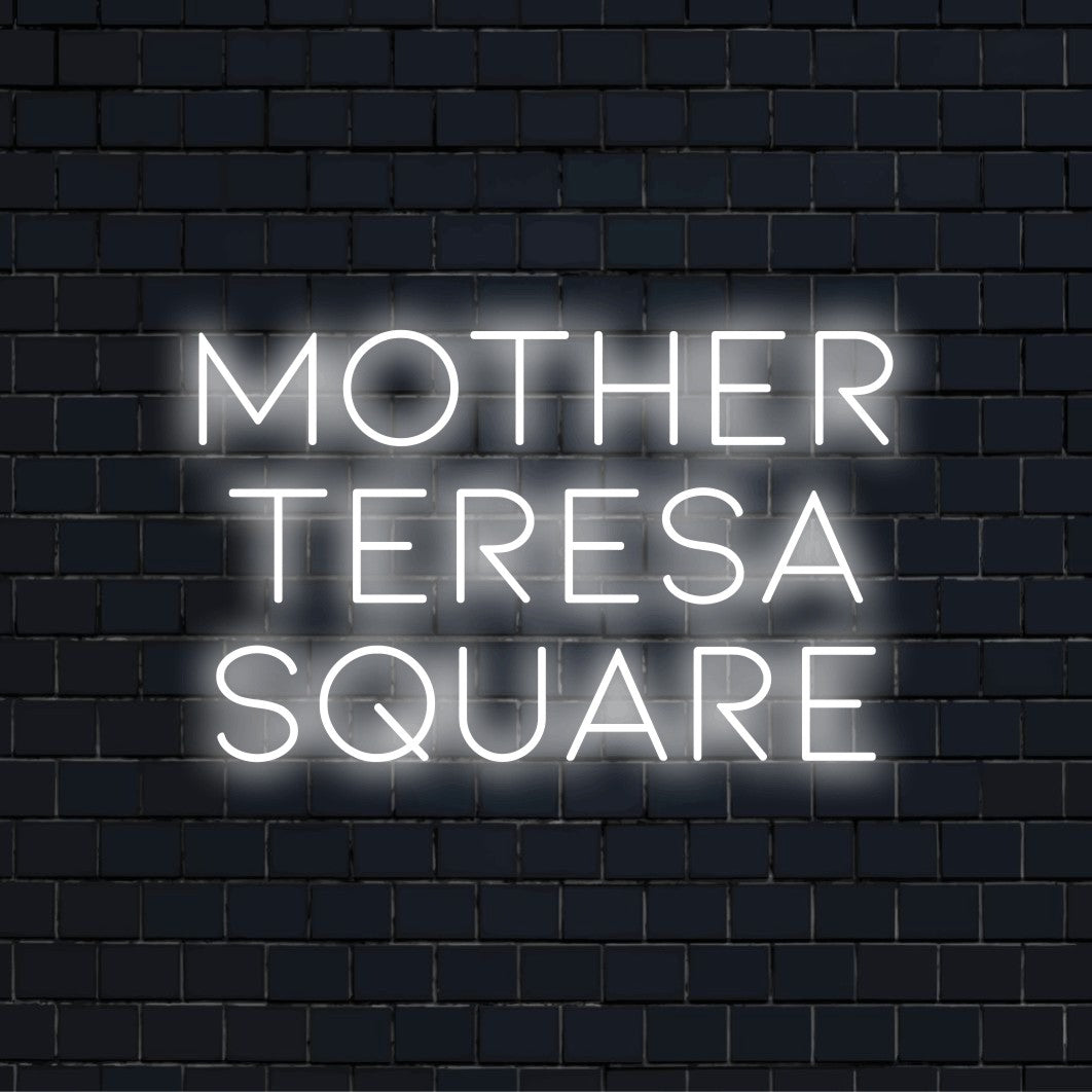 Mother Teresa Square Neon Sign, glowing lettering against brick backdrop