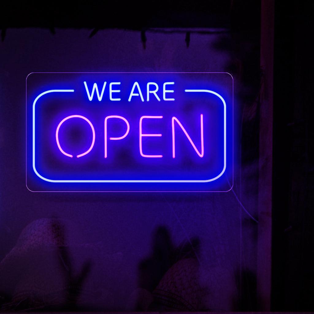 Vangitseva neonkyltti, jossa on ylpeänä sana "We are Open" lihavoituin, hehkuvin kirjaimin, mikä osoittaa, että yritys on valmis palvelemaan asiakkaitaan.