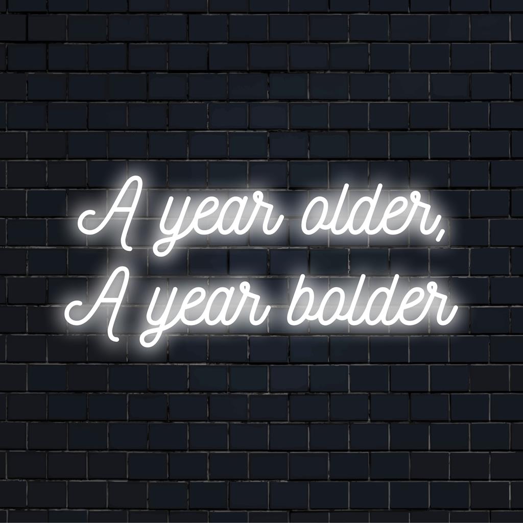 Livlig LED-neonskylt med texten A Year Older, A Year Bolder som slående neonväggkonst och anpassad ljusdekor.