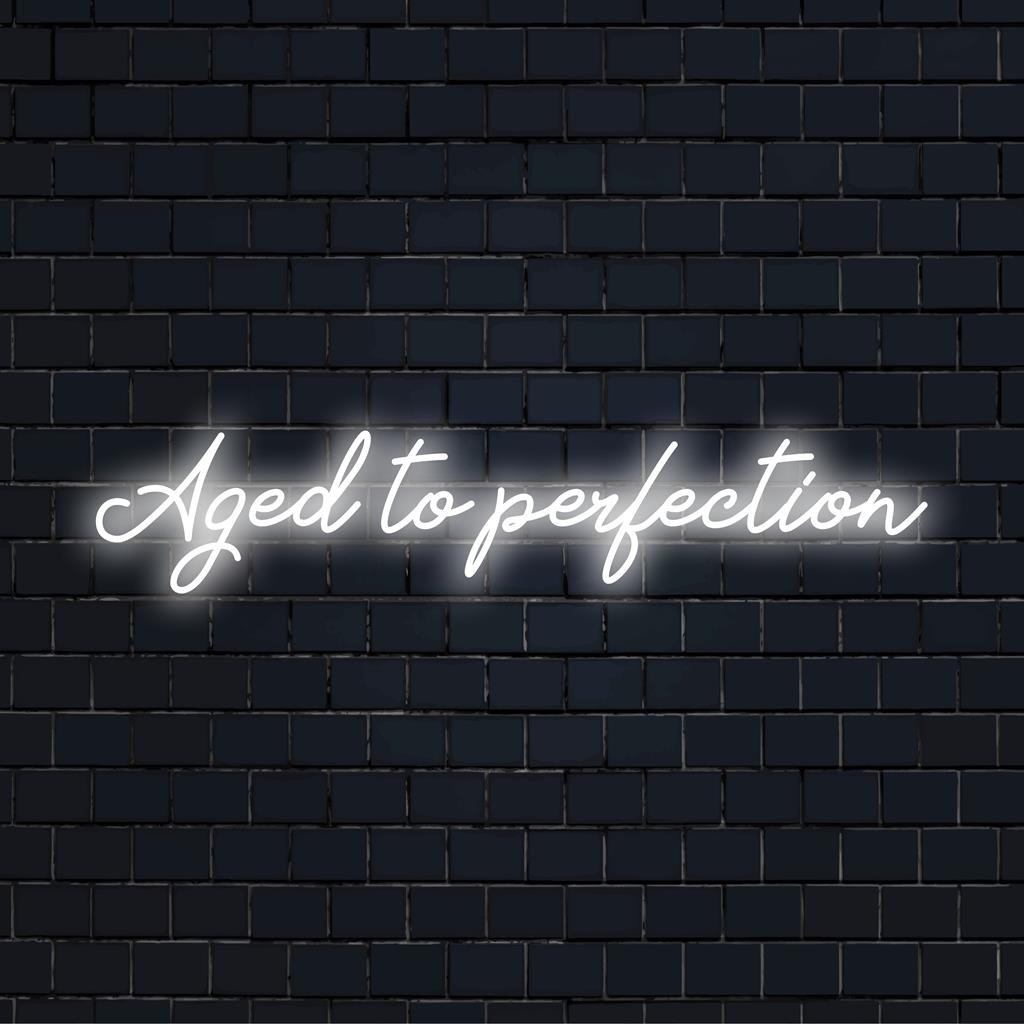 LED-neonskylt som visar Aged To Perfection i stilfullt manus, perfekt för att ge en personlig touch till alla utrymmen.