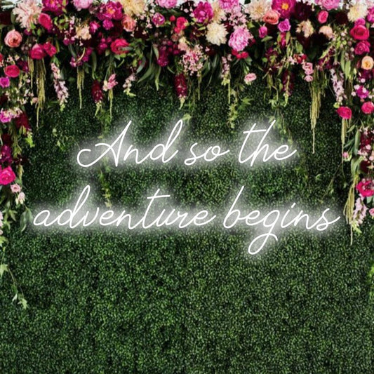 Mukautettu LED-neonkyltti lauseella And So The Adventure Begins hehkuu eloisasti, täydellinen yksilölliseen seinäsisustukseen.