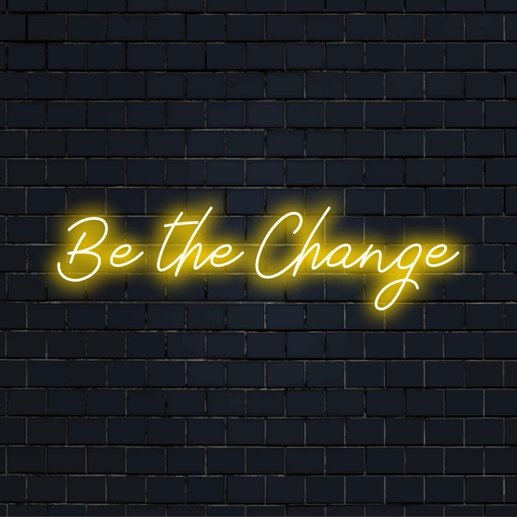 Custom made LED neon sign spelling Be The Change, perfect for adding inspiring neon light decor to any space.