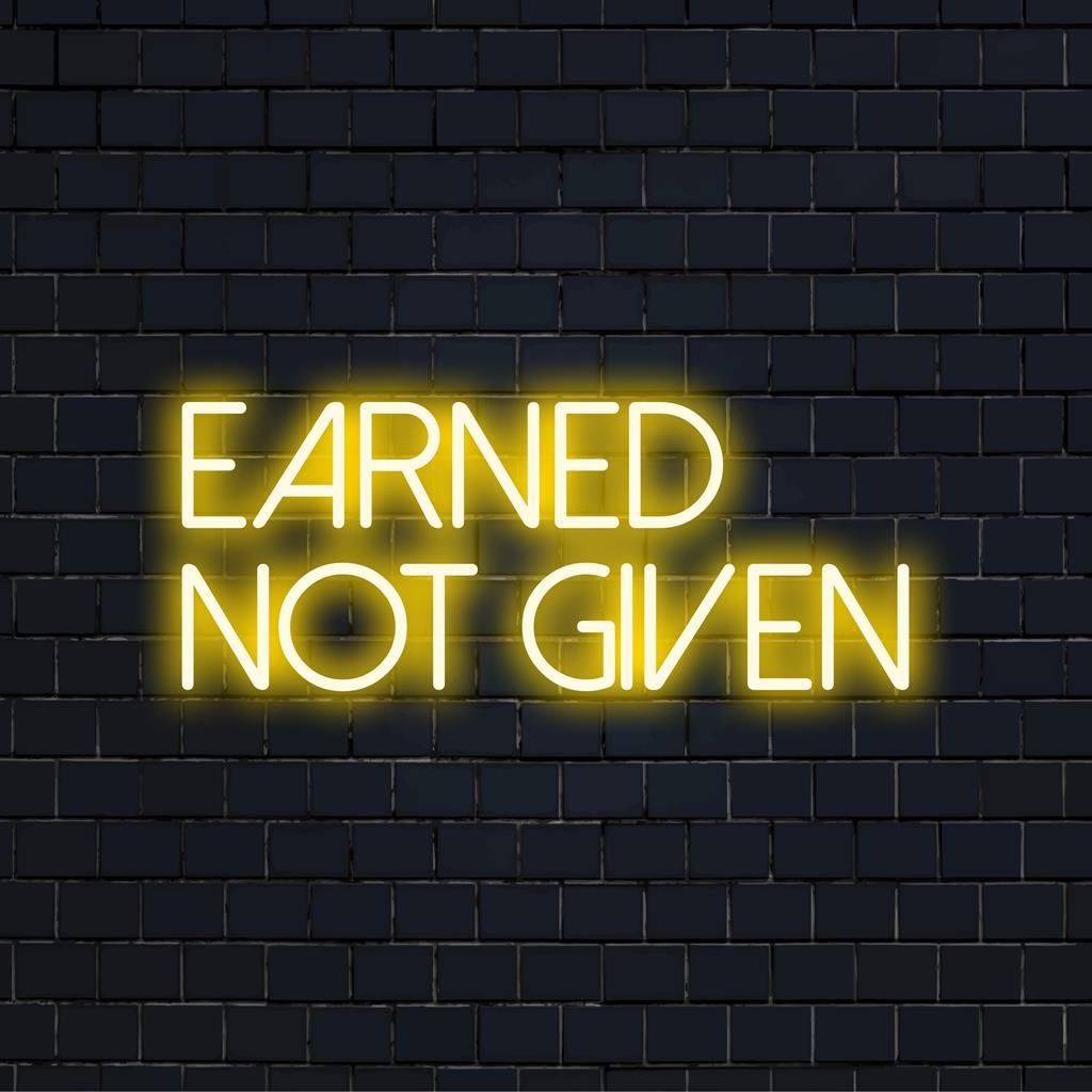 Anpassad LED-neonskylt från märket Art Neon, med den inspirerande frasen Earned Not Given i livfulla, glödande bokstäver.