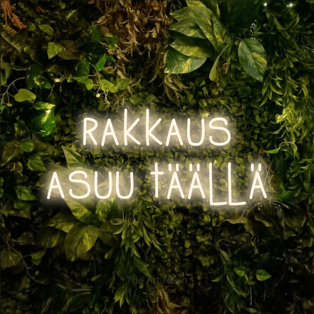 LED neon sign reading “rakkaus asuu täällä”, arranged in 2 lines.