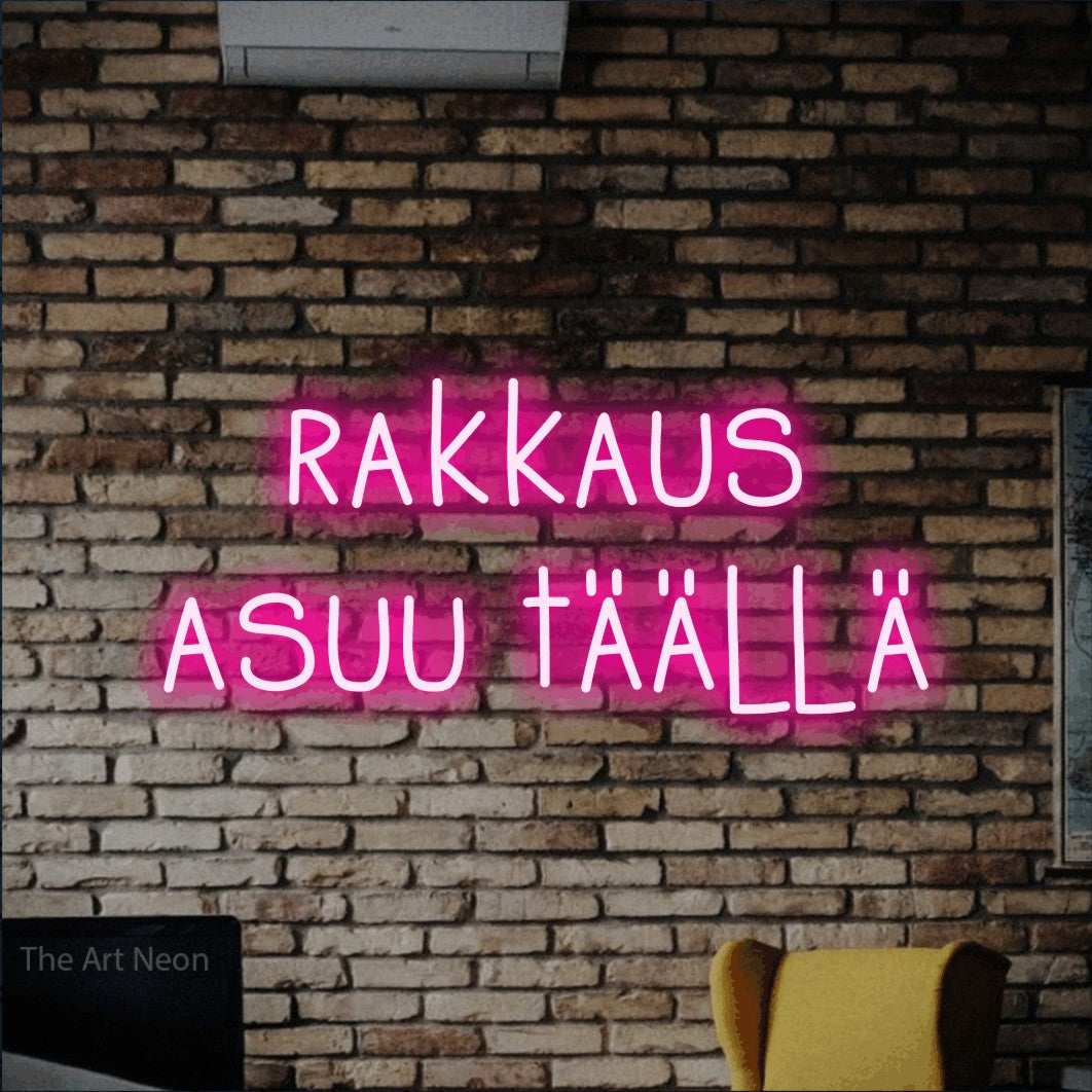 LED neon sign reading “rakkaus asuu täällä”, arranged in 2 lines.