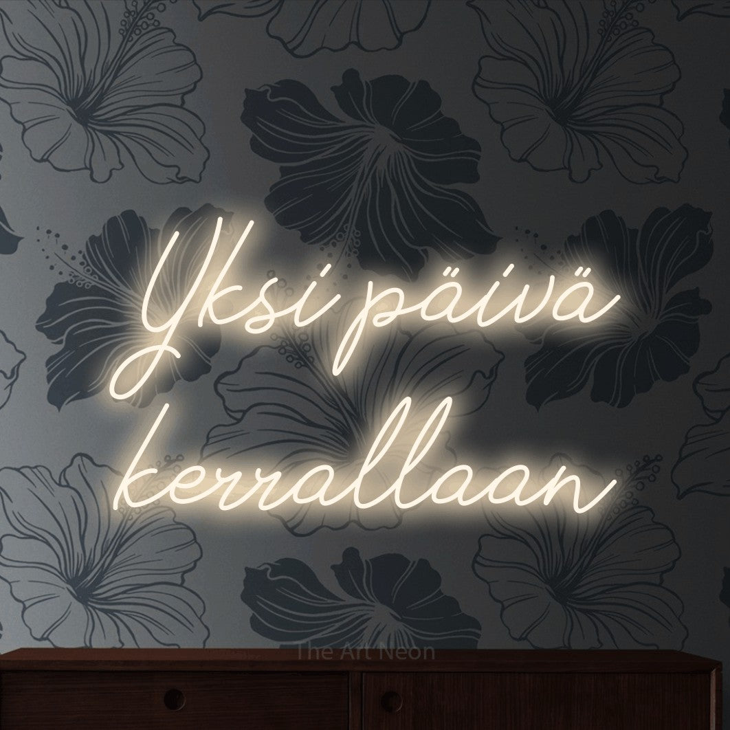 LED neon sign reading “Yksi päivä kerrallaan”, arranged in 2 lines.