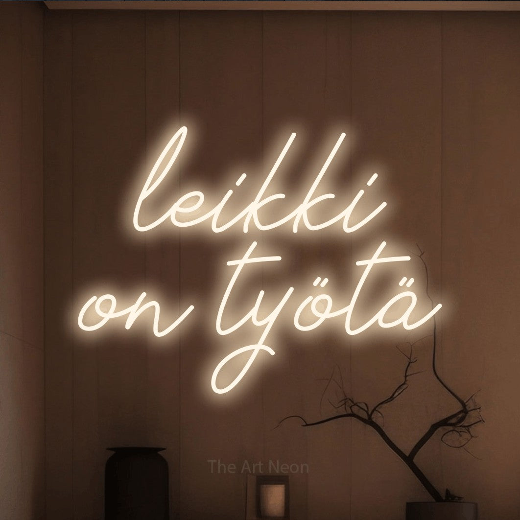 LED neon sign reading “leikki on työtä”, arranged in 2 lines.