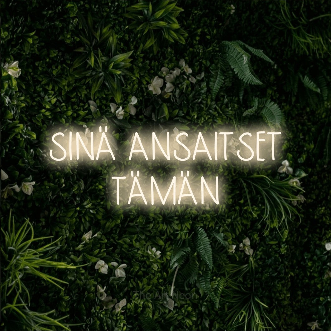 LED neon sign reading “SINÄ ANSAITSET TÄMÄN”, arranged in 2 lines.