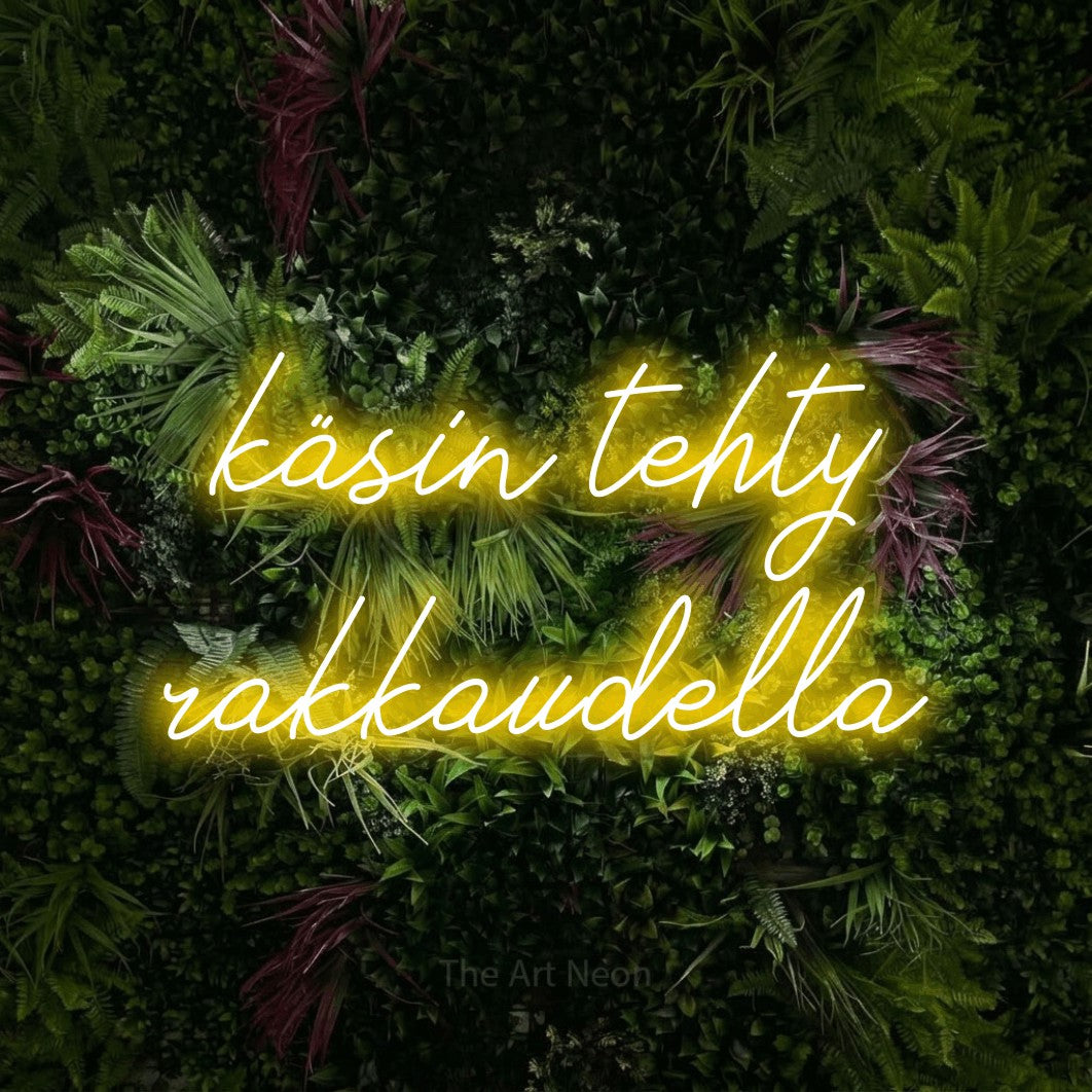 LED neon sign reading “käsin tehty rakkaudella”, arranged in 2 lines.