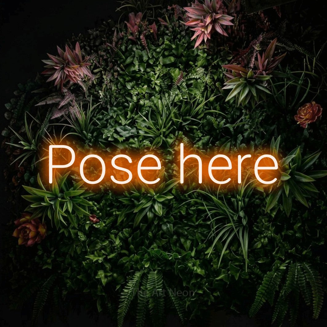 LED neon sign reading “Pose here”, arranged in a single line.