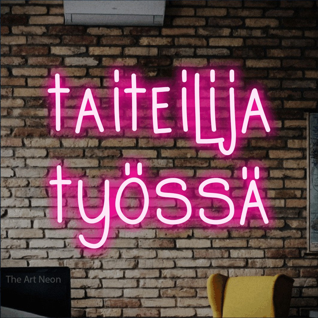 LED neon sign reading “taiteilija työssä”, arranged in 2 lines.