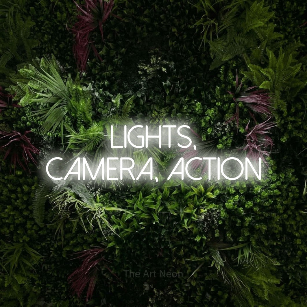 LED neon sign reading “lights, camera, action”, arranged in 2 lines.