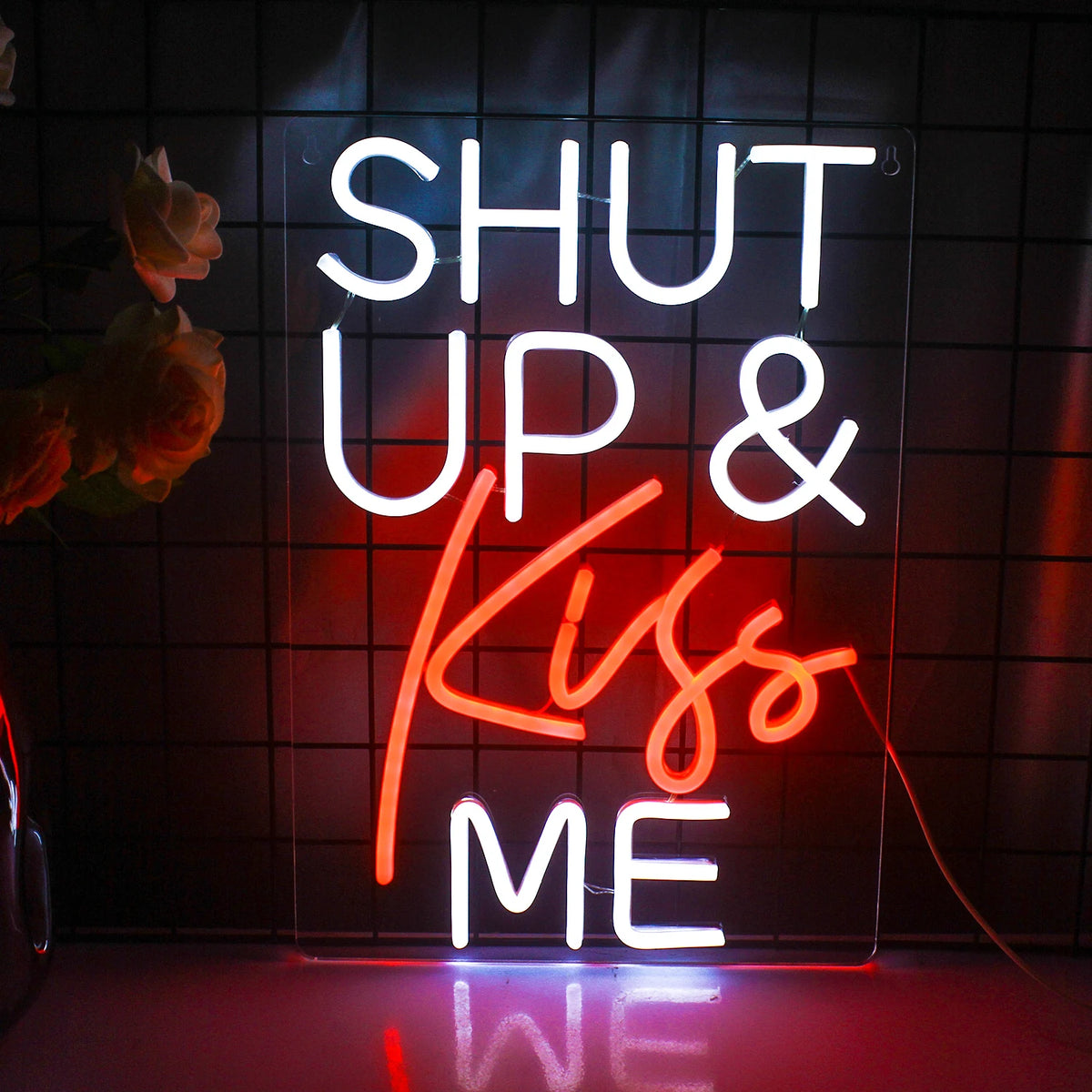 Kuvassa on eloisa LED-valokyltti, jossa lukee "Shut Up Kiss Me" leikkisällä, kursiivisella käsikirjoituksella.