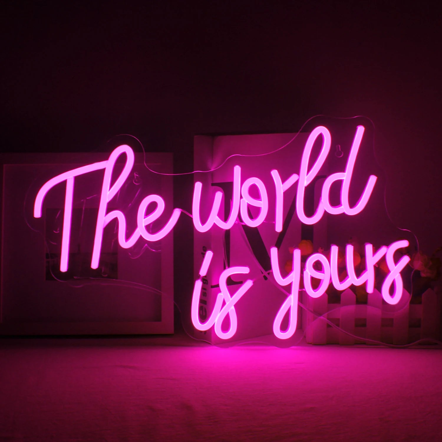 A vibrant LED neon sign displaying the words "The World Is Yours" in a stylish, cursive font.