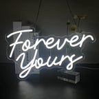 A vibrant LED neon sign displaying the phrase "Forever Yours" in elegant cursive lettering.