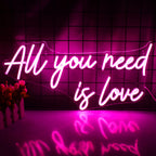 Kuvassa on eloisa LED-valokyltti, jossa on teksti "All You Need is Love" eleganteilla ja kursiivisilla kirjaimilla.