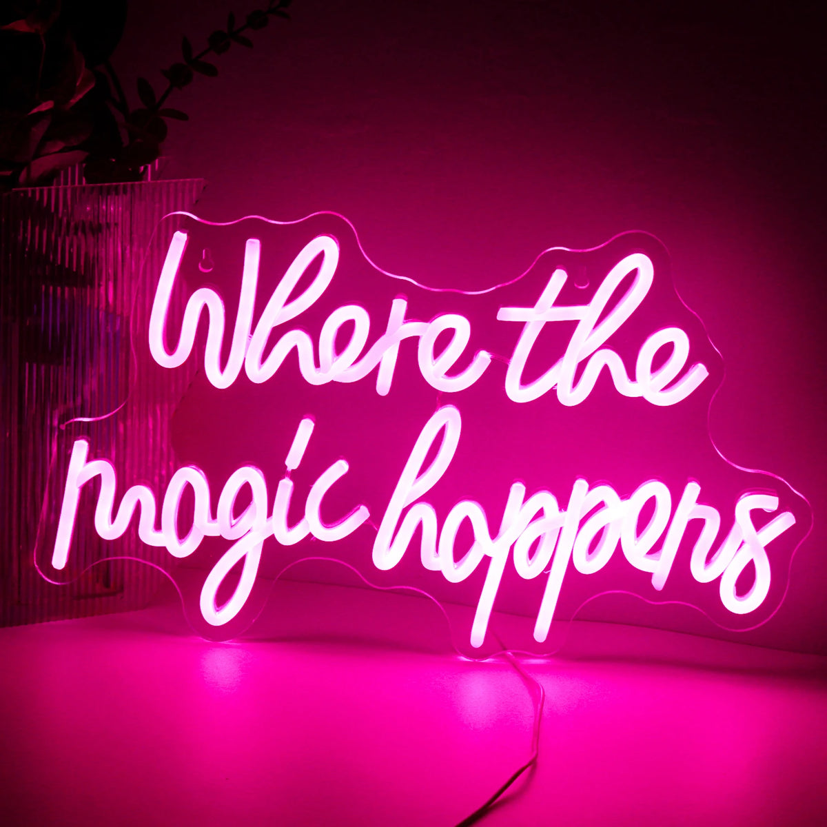Kuvassa on eloisa LED-valokyltti, jossa lukee "Where The Magic Happens" tyylikkäällä, leikkisällä kirjasintyypillä.