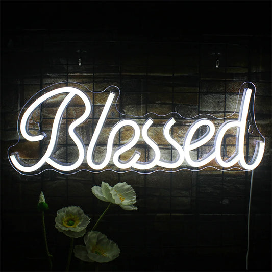 A vibrant "Blessed" LED neon sign is mounted against a dark wall, emitting a warm, inviting glow.