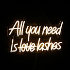 Kuvassa on eloisa LED-valokyltti, jossa on teksti "All You Need is Lashes" eleganteilla ja kursiivisilla kirjaimilla.