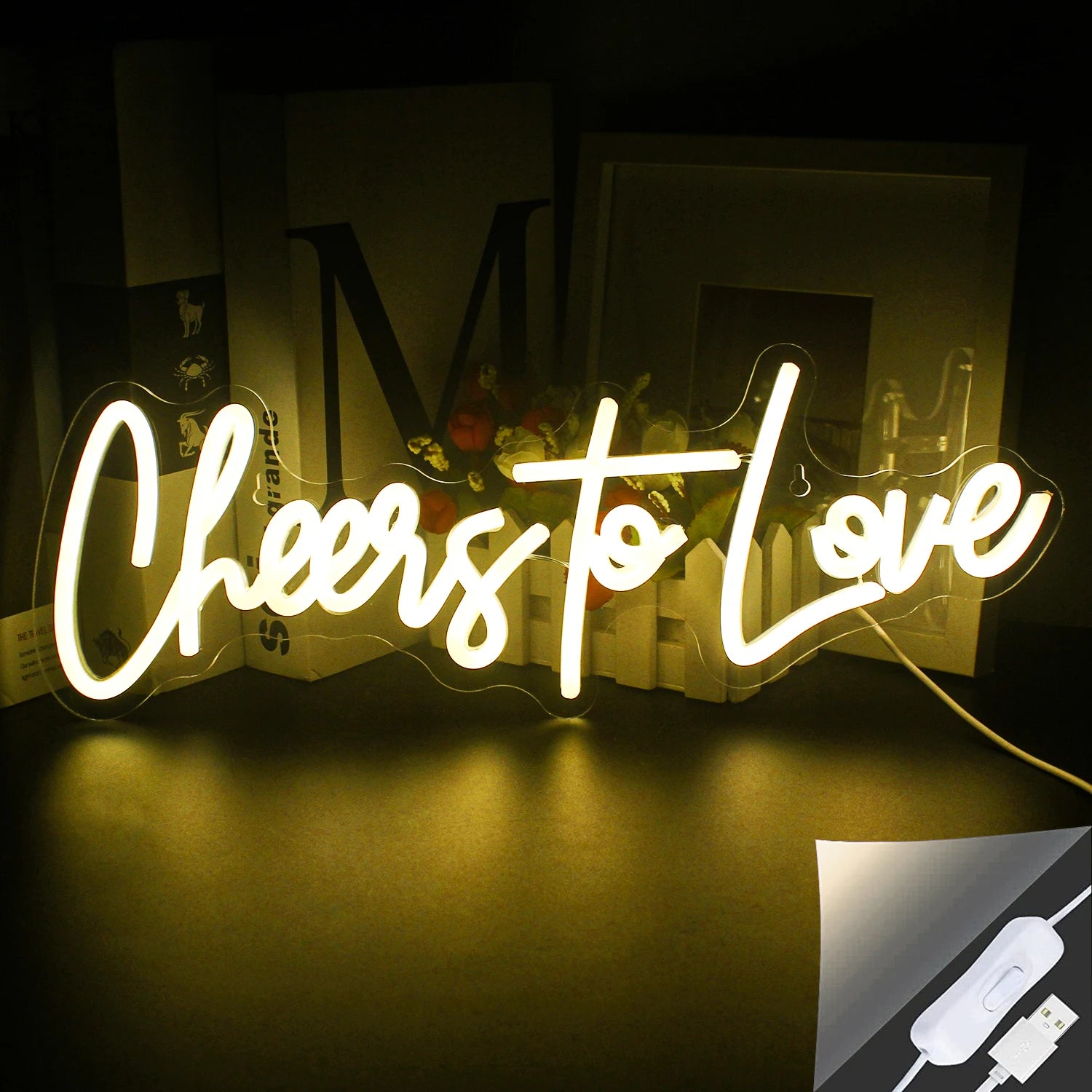 The image displays a vibrant, handmade LED neon sign that spells out "Cheers to Love" in a stylish script font.