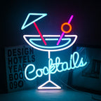 Kuvassa on eloisa LED-neonkyltti, jossa näkyy sana "cocktails" leikkisällä, kursiivisella fontilla.