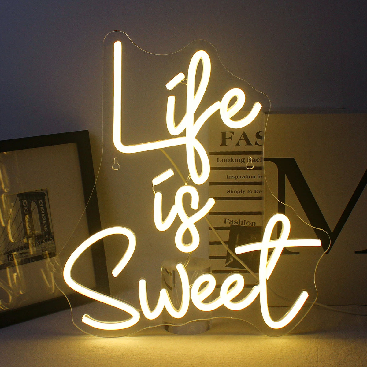 Kuvassa on eloisa, käsintehty LED-neonkyltti kirkkaissa, hehkuvissa väreissä, jotka ilmaisevat lauseen "Life is Sweet.