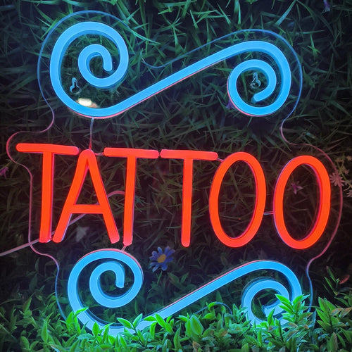 Valaistu LED-valokyltti kirjoittaa sanan "TATTOO" lihavoin, isoilla kirjaimilla.