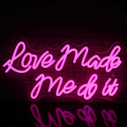 Kuvassa on eloisa LED-valokyltti, jossa on sanat "Love Made Me Do It" tyylikkäällä kursiivikirjasimella.