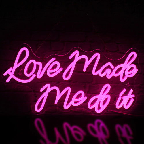 Kuvassa on eloisa LED-valokyltti, jossa on sanat "Love Made Me Do It" tyylikkäällä kursiivikirjasimella.