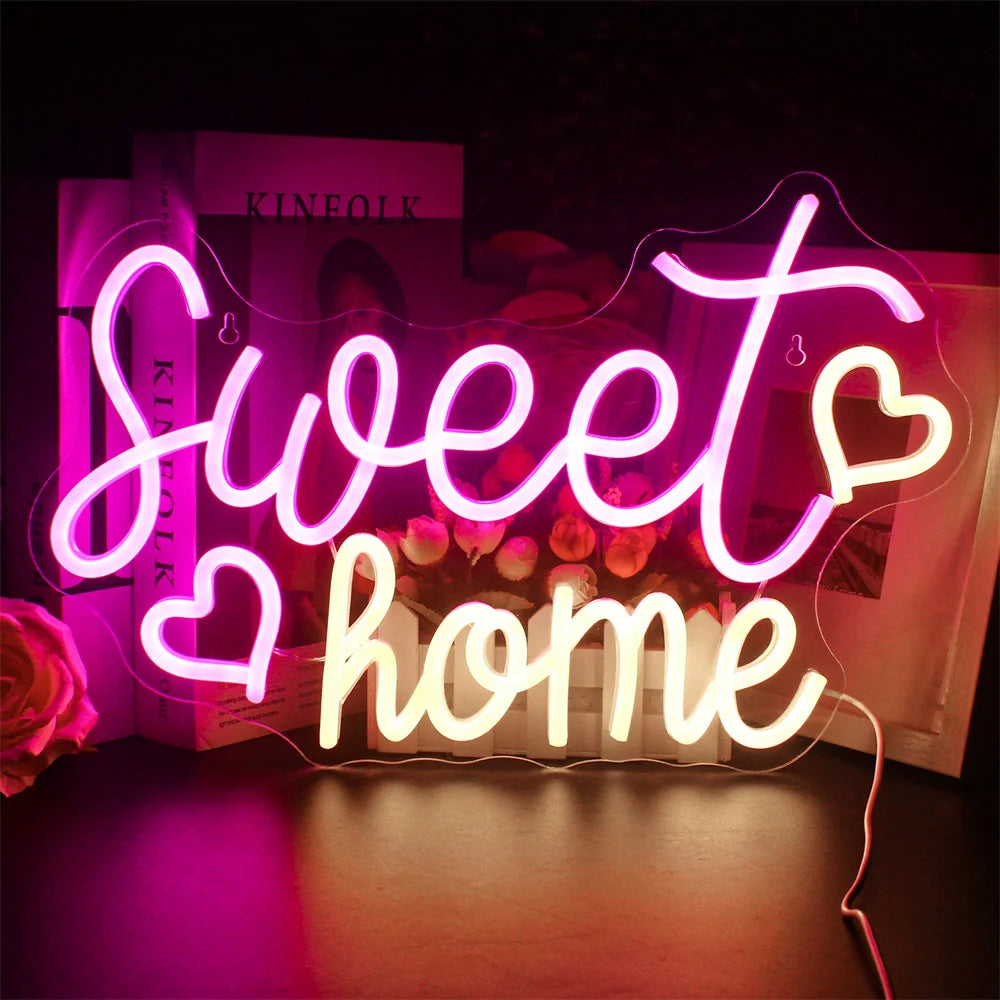 Kuvassa on eloisa, käsintehty LED-valokyltti, jossa on teksti "Sweet Home" tyylikkäällä kursiivisella tekstillä.