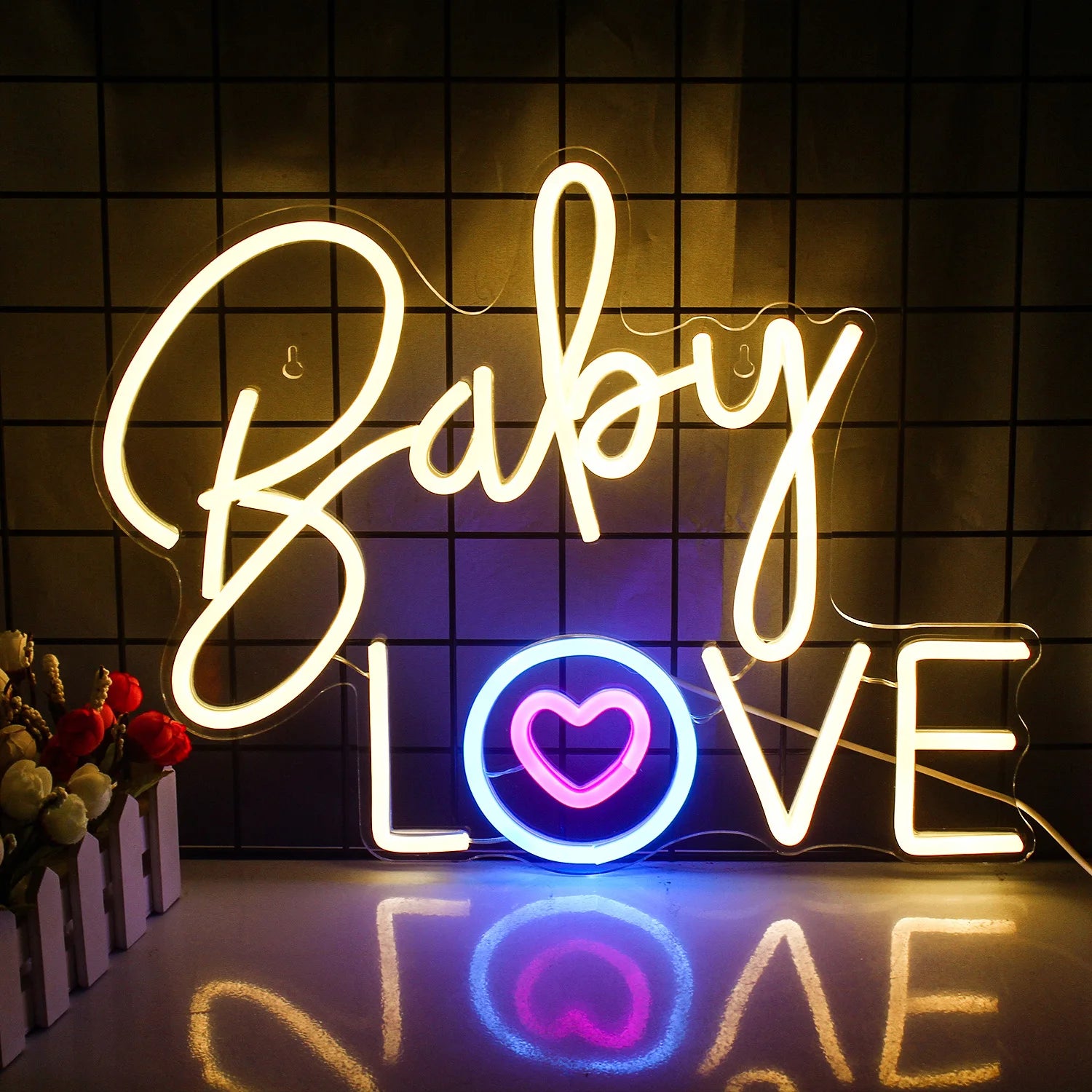 Eloisa vaaleanpunainen neonkyltti kirjoittelee sanat "Baby Love" leikkisällä, kursiivisella fontilla.