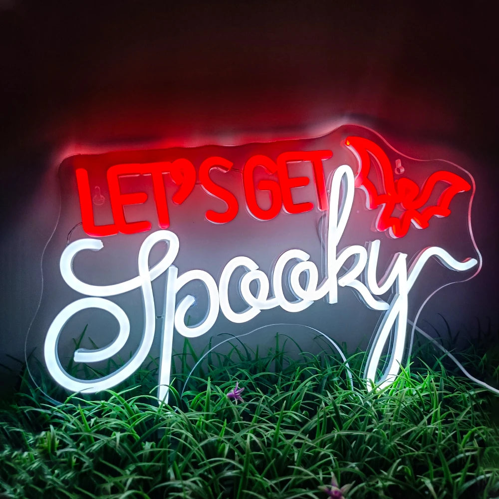 Kuvassa on eloisa LED-valokyltti, jossa on sanat "Let's Get Spooky" lihavoitulla, omituisella fontilla.