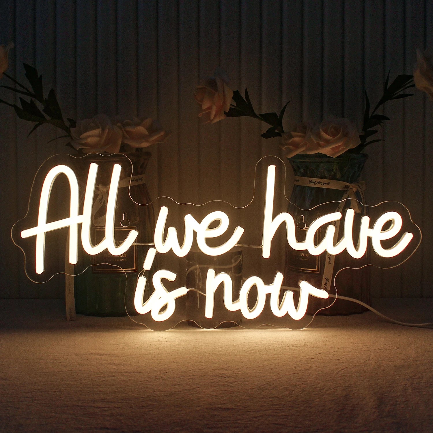 Kuvassa on käsintehty LED-valokyltti, jossa on sanat "All We Have Is Now" kirkkain, kirkkain kirjaimin.