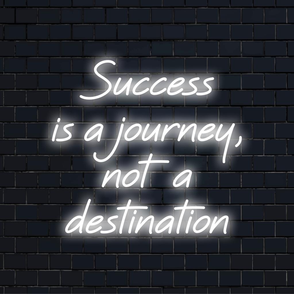 Mukautettu LED-valokyltti, joka valaisee lauseen Success Is A Journey, Not A Destination kirkkaassa taiteellisessa neontypografiassa.