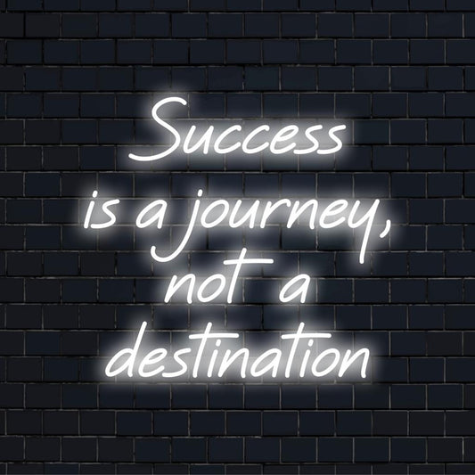Mukautettu LED-valokyltti, joka valaisee lauseen Success Is A Journey, Not A Destination kirkkaassa taiteellisessa neontypografiassa.