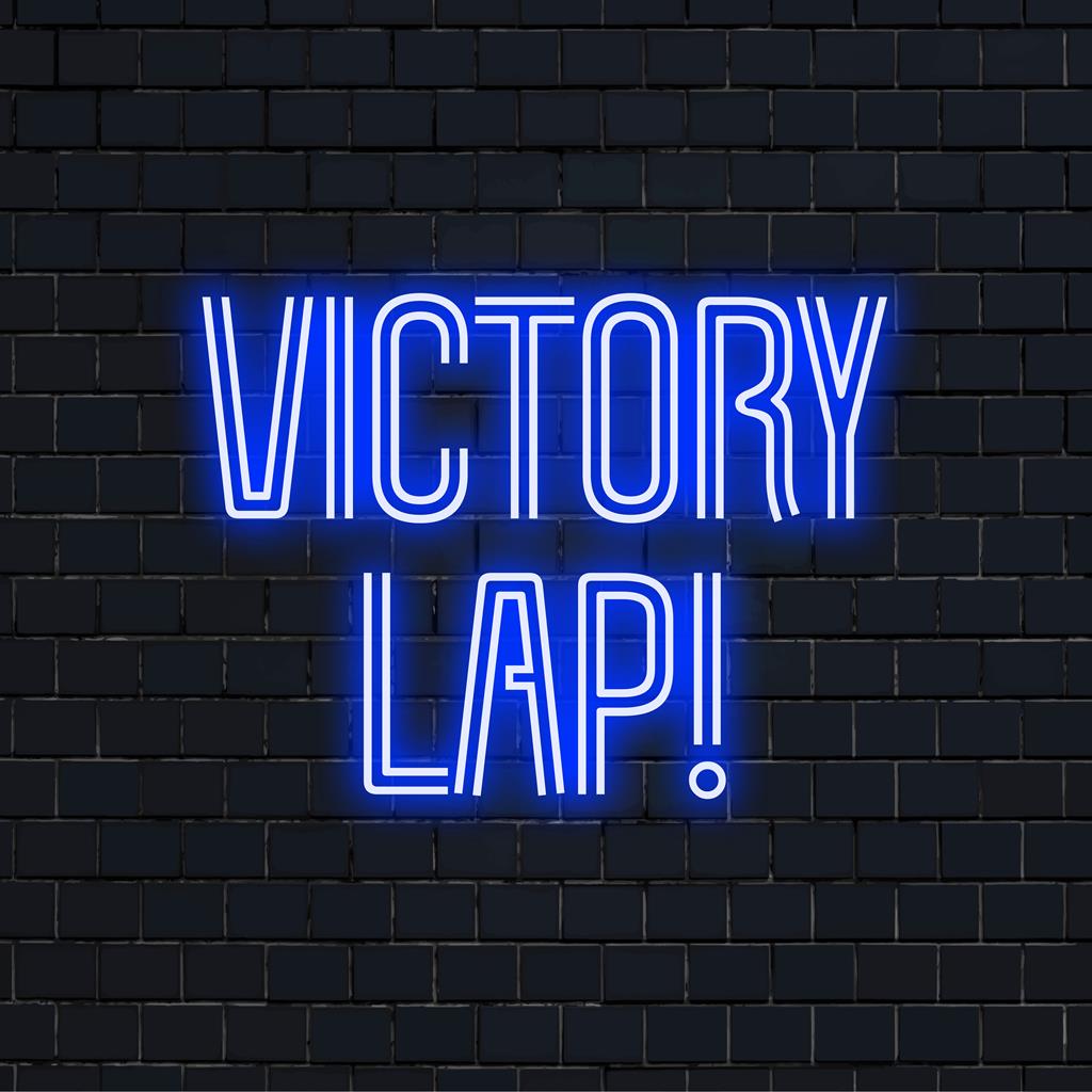 Mukautettu neonkyltti lauseella Victory Lap! kirkkaissa väreissä valaisee kaikkia tiloja ja sopii täydellisesti persoonalliseen neonkoristeeseen.