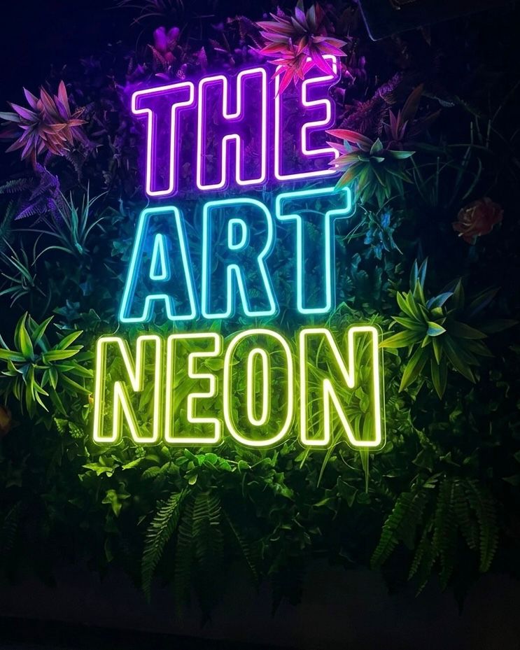 Monivärinen The Art Neon -LED-neonkyltti kasvien keskellä