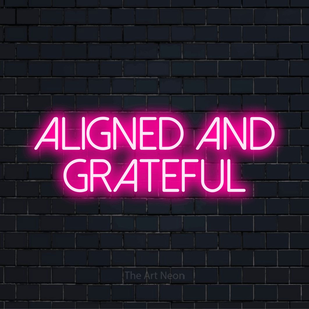 "Aligned And Grateful" script-style LED neon sign on a black brick wall