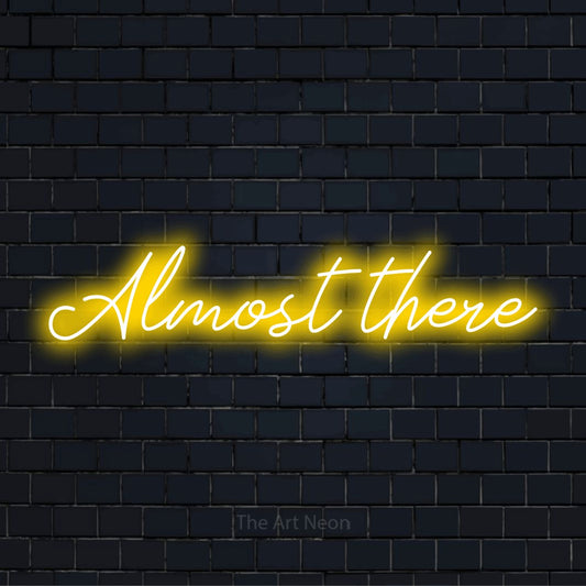 "Almost There" neon text design on a black brick wall