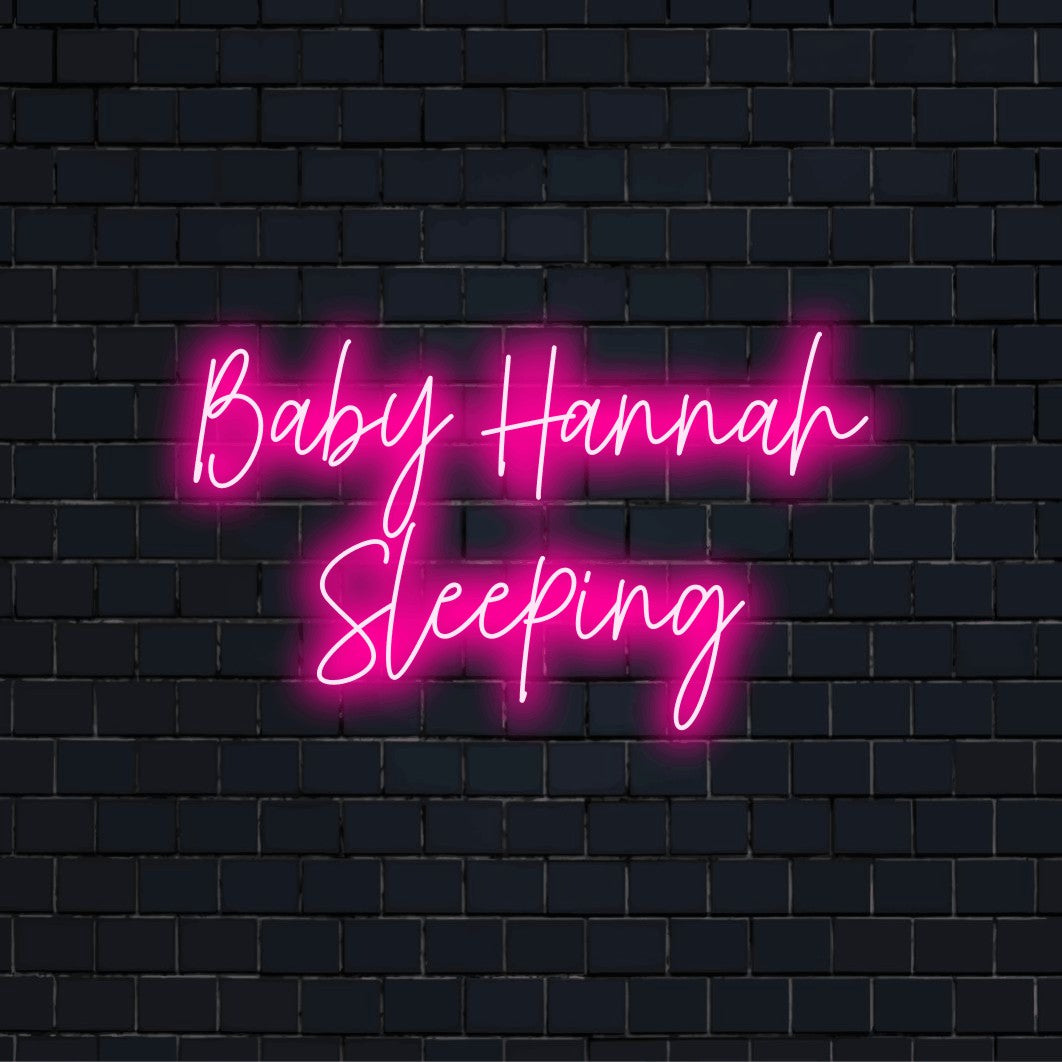 Baby Hannah Sleeping Custom Name Neon Sign, glowing neon text against black brick wall