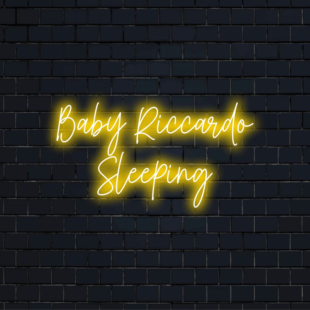 Baby Riccardo Sleeping Personalized LED Neon Sign, bright neon lettering on dark brick wall