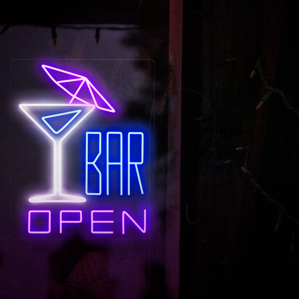 Kuvassa on neonkyltti, jonka vasemmalla puolella on cocktail sateenvarjolla ja oikealla teksti "avoin baari". Tämä neonkyltti sopii erinomaisesti baareihin, sekä sisä- että ulkotiloihin.