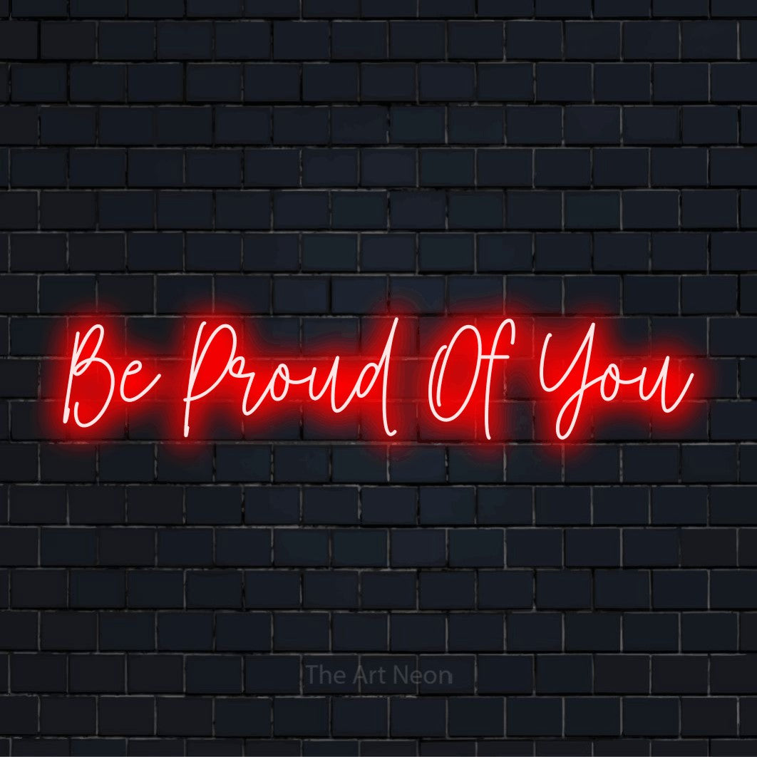 "Be Proud Of You" glowing LED neon sign on a black brick wall