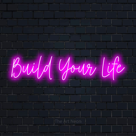 "Build Your Life" neon text design on a black brick wall