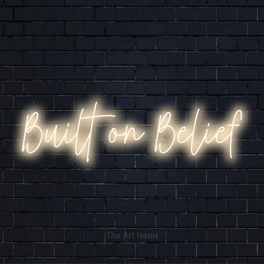 "Built On Belief" LED neon sign on a black brick wall