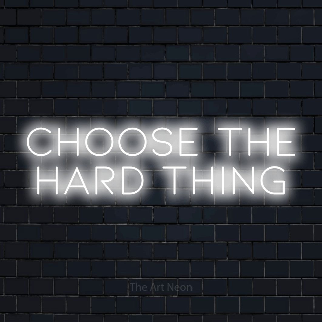 "Choose The Hard Thing" LED neon sign on a black brick wall